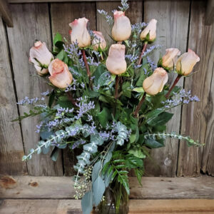 Long stem roses arranged in a vase with greenery and fillers
