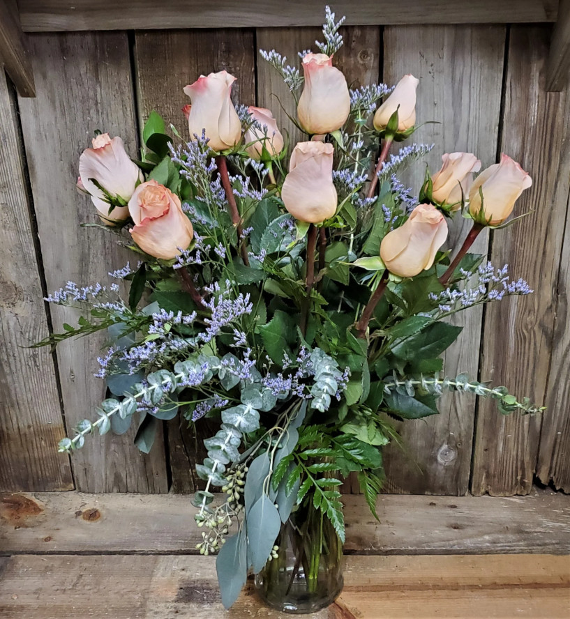 Long stem roses arranged in a vase with greenery and fillers